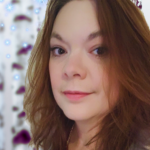 TF Burke, YA fantasy author of the Heart of the Worlds series, smiling outside with red hair